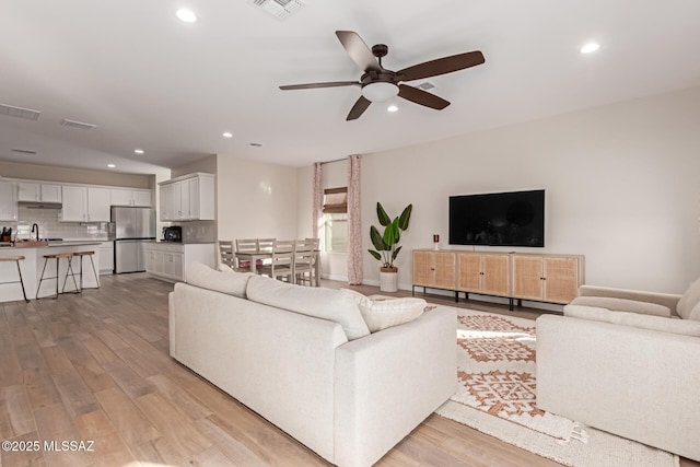 living room with ceiling fan, recessed lighting, visible vents, and light wood-style floors