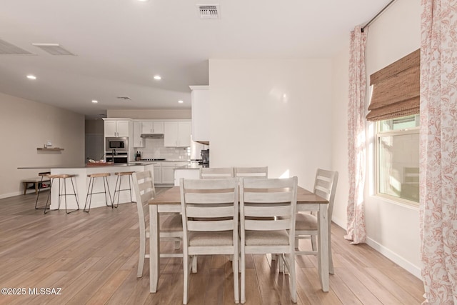 dining space with light wood-type flooring, baseboards, and visible vents