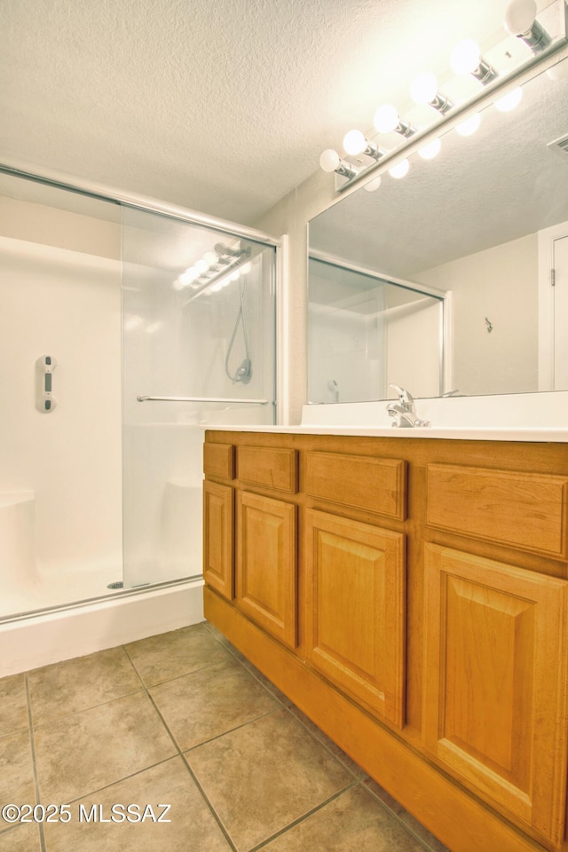 full bathroom with a shower stall, tile patterned floors, vanity, and a textured ceiling