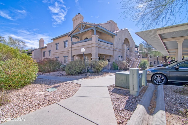 view of property exterior with stucco siding, stairway, and a chimney