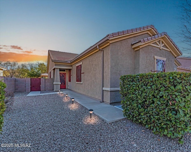 view of home's exterior with a tile roof, a patio area, fence, and stucco siding