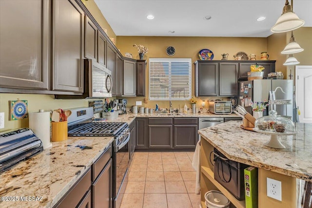 kitchen with hanging light fixtures, dark brown cabinetry, appliances with stainless steel finishes, and a sink