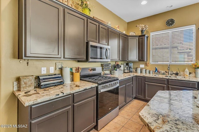 kitchen with light stone countertops, stainless steel appliances, a sink, and light tile patterned flooring