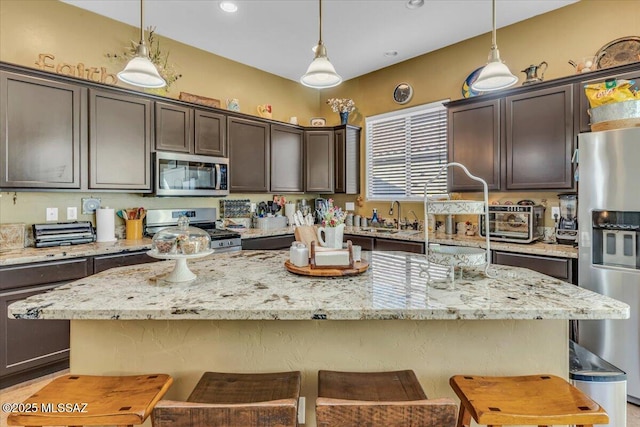 kitchen featuring stainless steel appliances, dark brown cabinetry, and pendant lighting