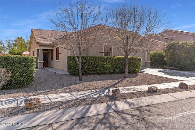 view of front facade featuring a garage, concrete driveway, and stucco siding