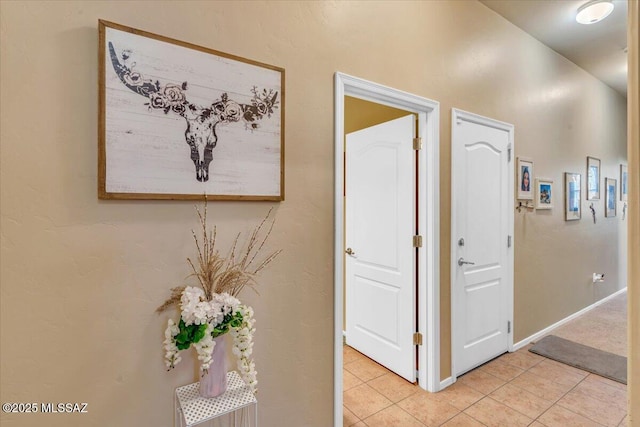 corridor with light tile patterned flooring and baseboards