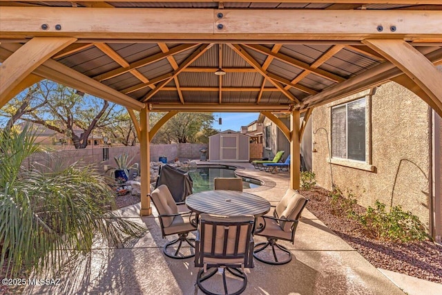 view of patio with a shed, a fenced backyard, an outdoor structure, a gazebo, and outdoor dining space