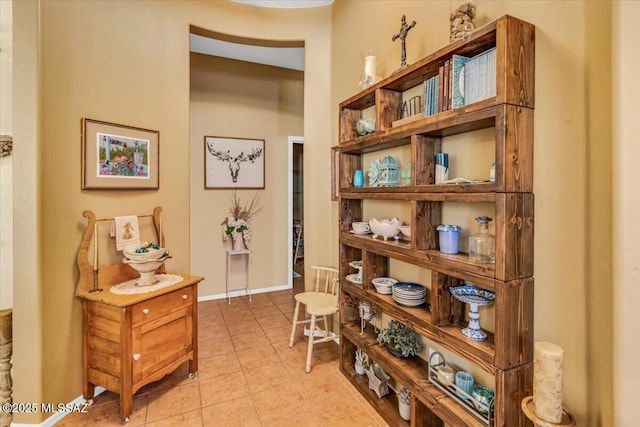 hall featuring light tile patterned flooring and baseboards