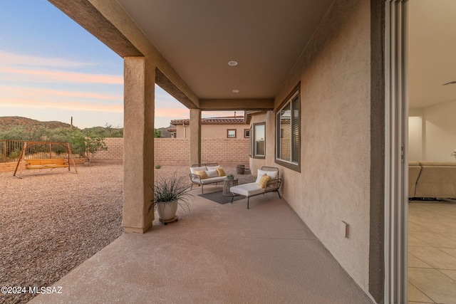 patio terrace at dusk with an outdoor hangout area, a playground, and a fenced backyard