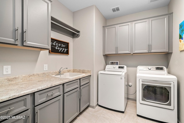 clothes washing area featuring visible vents, light tile patterned floors, washer and dryer, cabinet space, and a sink