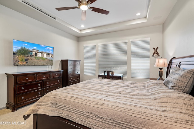 bedroom featuring baseboards, light colored carpet, a tray ceiling, recessed lighting, and a ceiling fan