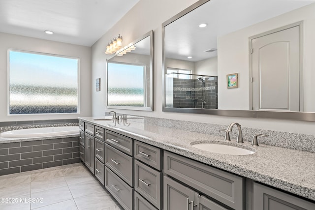 bathroom with double vanity, a sink, a shower stall, a garden tub, and tile patterned floors