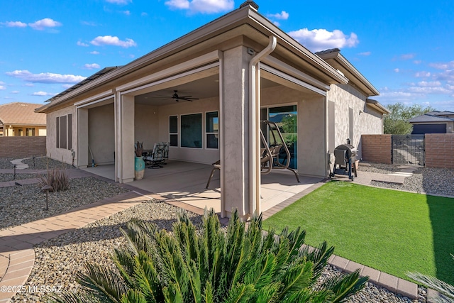 back of house featuring a gate, fence, ceiling fan, stucco siding, and a patio area