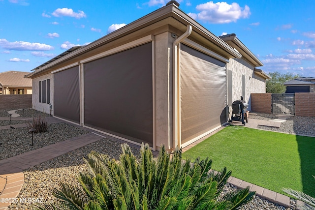 view of home's exterior with fence, stucco siding, a lawn, a patio area, and a gate