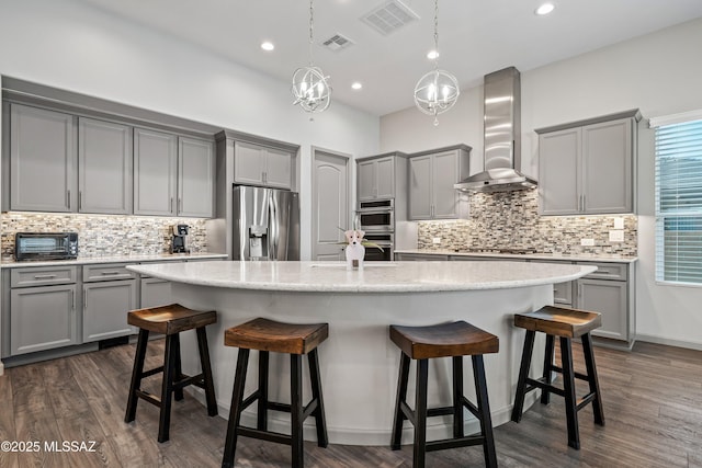 kitchen featuring stainless steel appliances, visible vents, gray cabinets, and wall chimney range hood