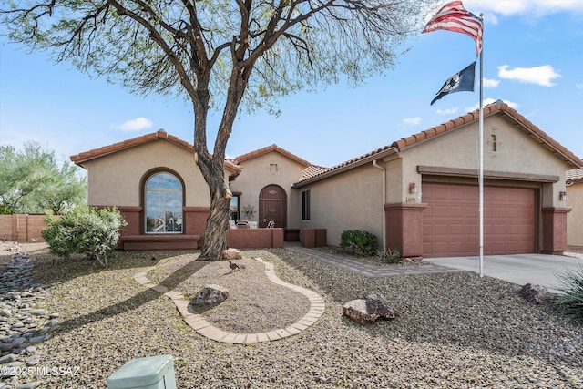 mediterranean / spanish home with driveway, a tiled roof, an attached garage, fence, and stucco siding