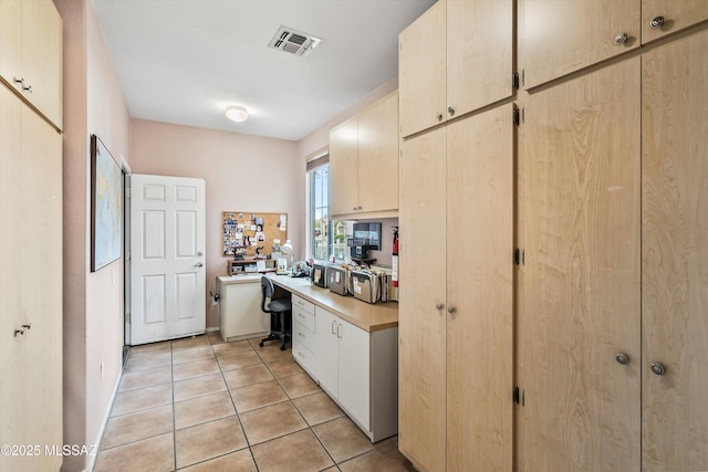 kitchen with light brown cabinetry, visible vents, light countertops, and light tile patterned flooring