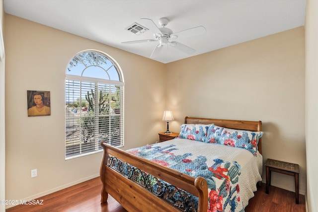 bedroom featuring a ceiling fan, wood finished floors, visible vents, and baseboards