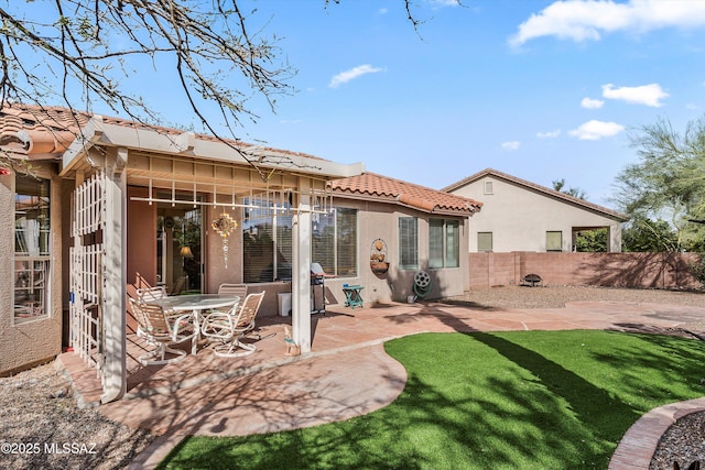 rear view of house featuring a lawn, a patio, a tile roof, fence, and stucco siding