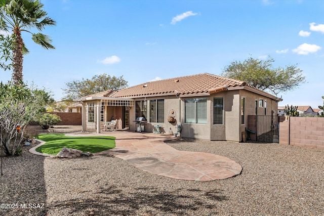 back of house featuring a patio area, a fenced backyard, a tile roof, and stucco siding