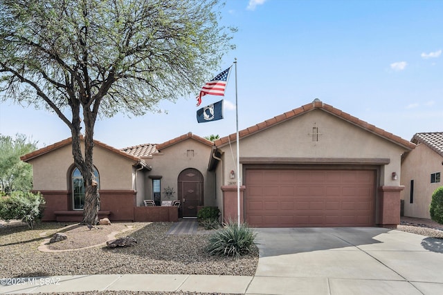 mediterranean / spanish-style home with a garage, driveway, and stucco siding