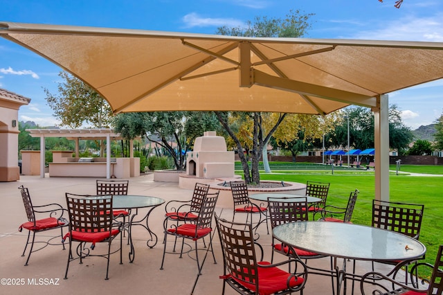 view of patio / terrace featuring exterior fireplace, outdoor dining area, area for grilling, and a pergola