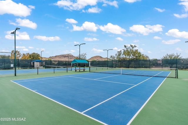 view of tennis court with fence and a mountain view