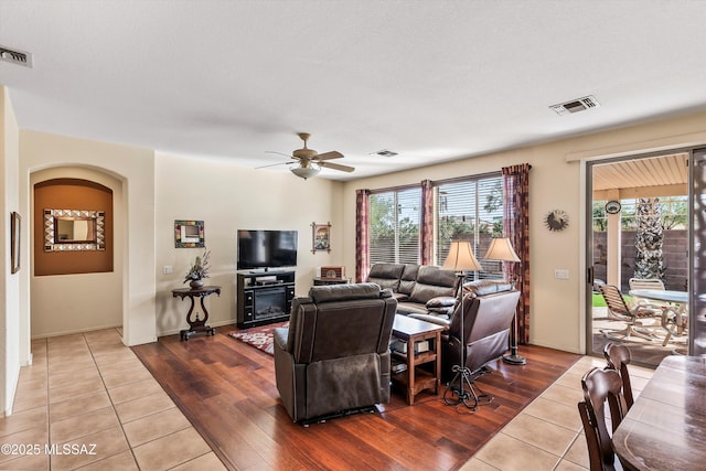 living area featuring arched walkways, visible vents, and wood finished floors