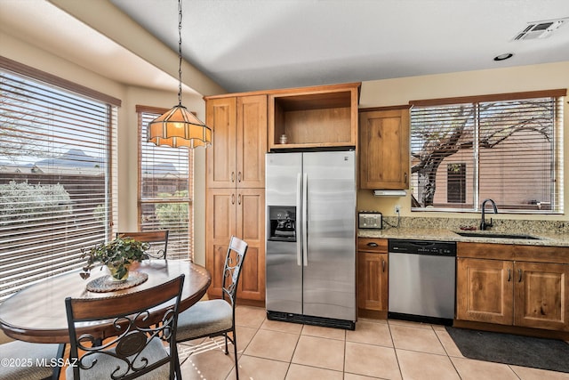 kitchen with light tile patterned flooring, a sink, visible vents, appliances with stainless steel finishes, and light stone countertops