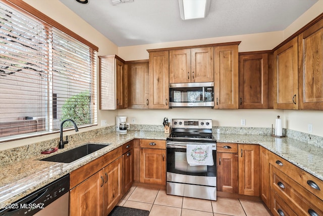 kitchen with stainless steel appliances, a sink, and brown cabinets