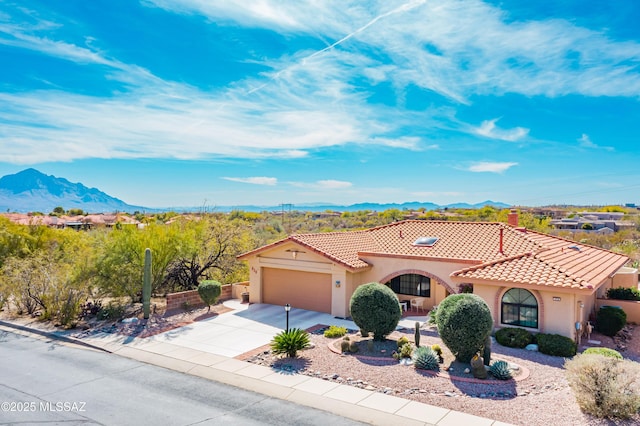 mediterranean / spanish-style home featuring an attached garage, a mountain view, concrete driveway, a tiled roof, and stucco siding