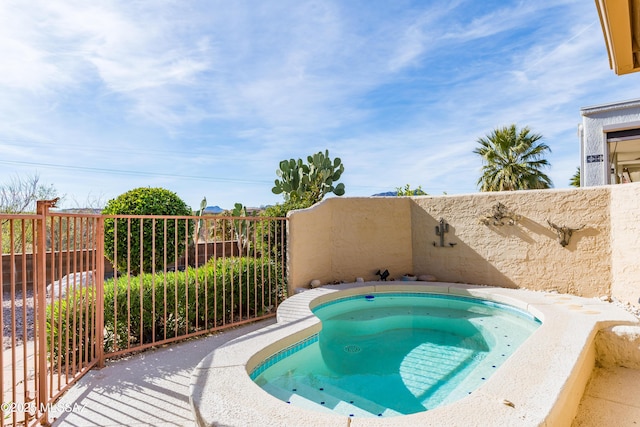 view of swimming pool with fence and an in ground hot tub