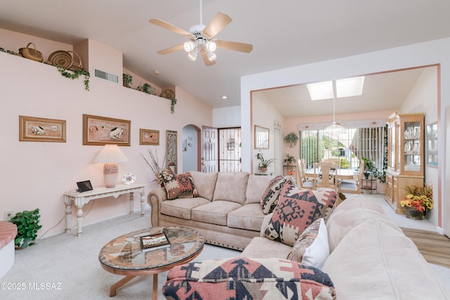 living room featuring arched walkways, visible vents, vaulted ceiling, and ceiling fan