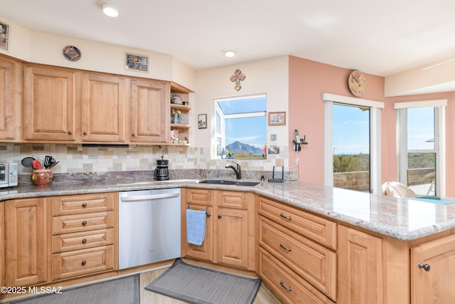 kitchen with tasteful backsplash, light stone counters, a peninsula, stainless steel dishwasher, and a sink