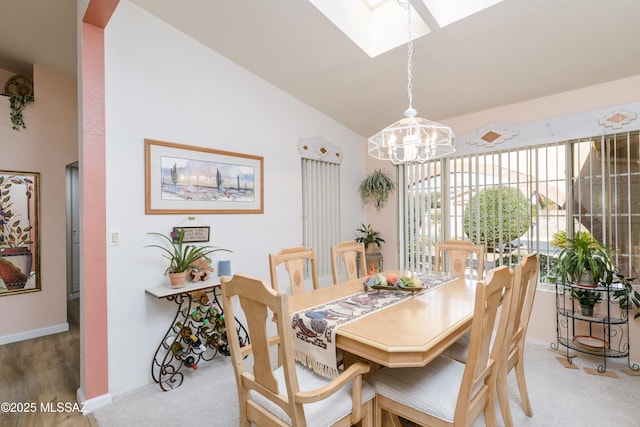 carpeted dining space with baseboards, lofted ceiling with skylight, and a notable chandelier