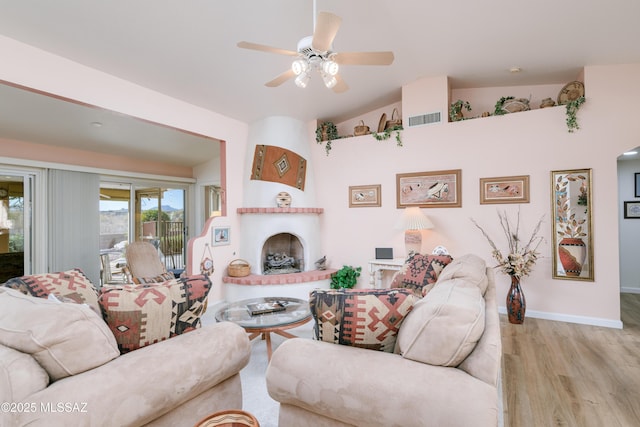 living room with lofted ceiling, a fireplace, wood finished floors, visible vents, and baseboards