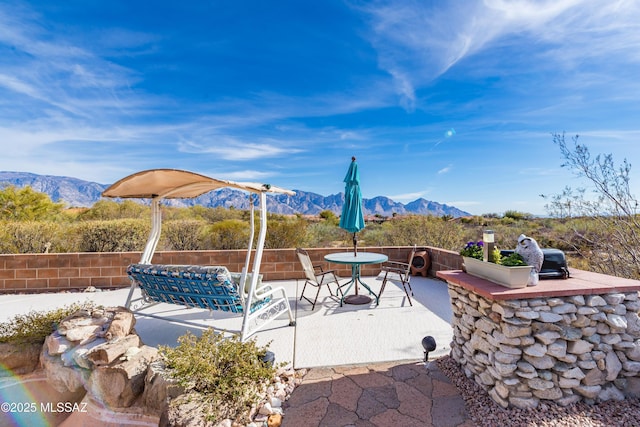 view of patio / terrace featuring fence, a mountain view, and outdoor dining area