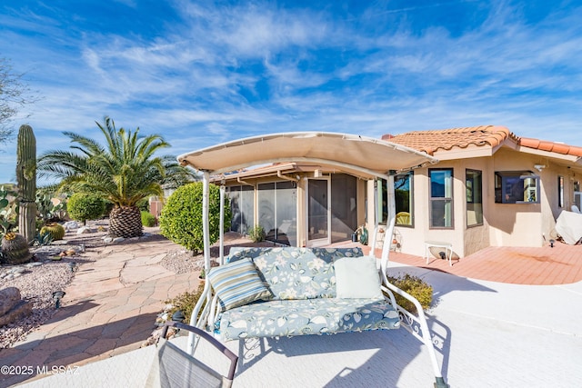 back of house with a patio, a tile roof, a sunroom, and stucco siding