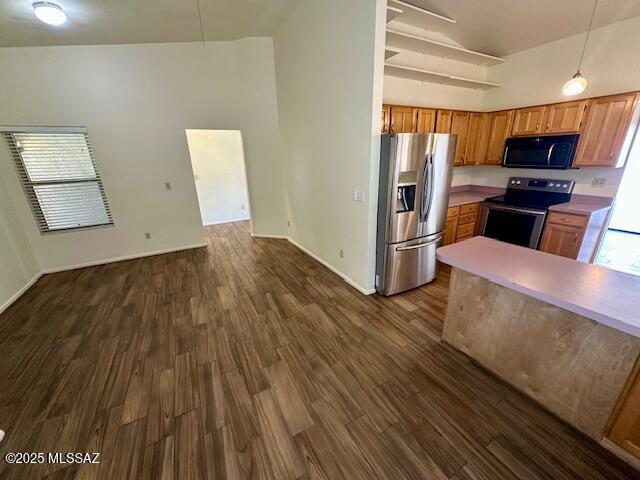 kitchen featuring stainless steel appliances, open floor plan, light countertops, and decorative light fixtures