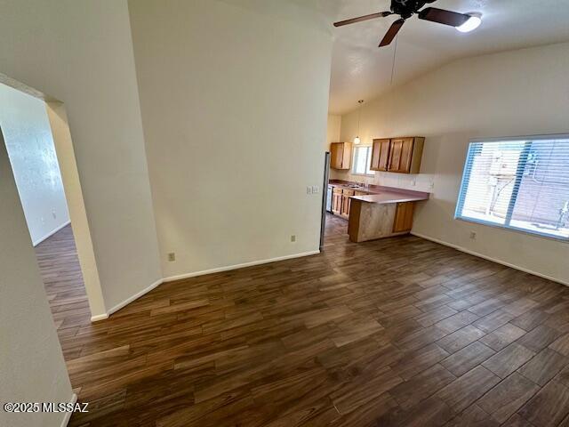 kitchen featuring brown cabinetry, light countertops, dark wood-style flooring, and open floor plan