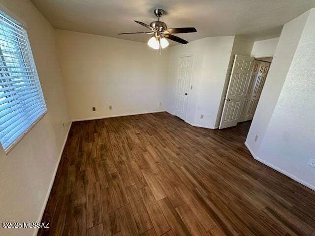 interior space featuring dark wood finished floors, a ceiling fan, and baseboards