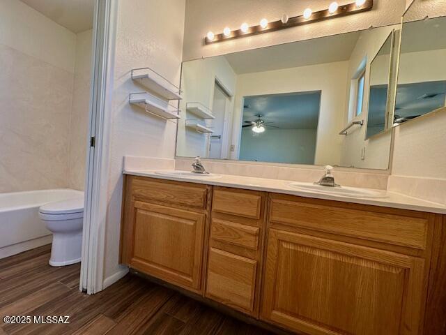 full bath featuring double vanity, wood finished floors, a sink, and toilet