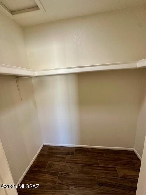 spacious closet with dark wood-style floors and attic access