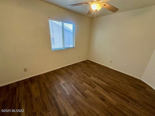 spare room featuring ceiling fan, dark wood-type flooring, and baseboards