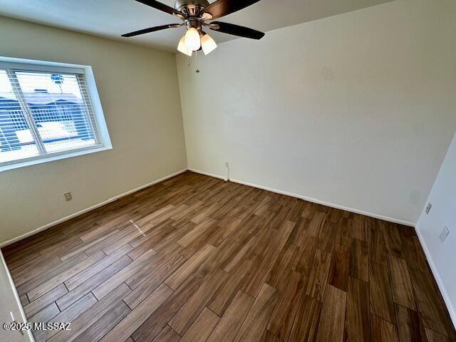 empty room with a ceiling fan, baseboards, and wood finished floors