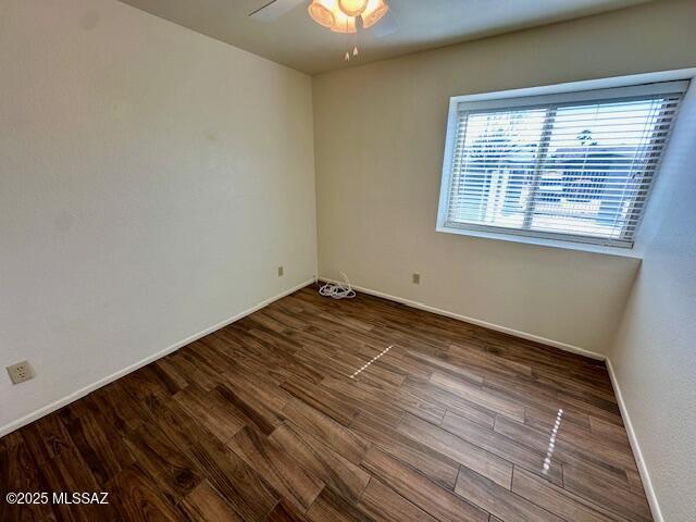 empty room featuring wood finished floors, a ceiling fan, and baseboards