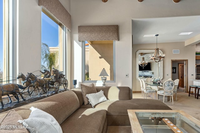 carpeted living area featuring baseboards, visible vents, and a notable chandelier