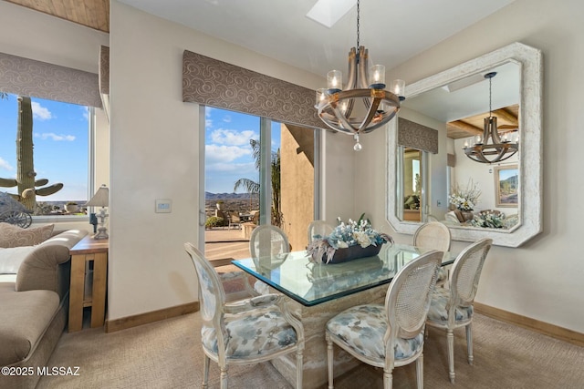 carpeted dining space with baseboards and an inviting chandelier