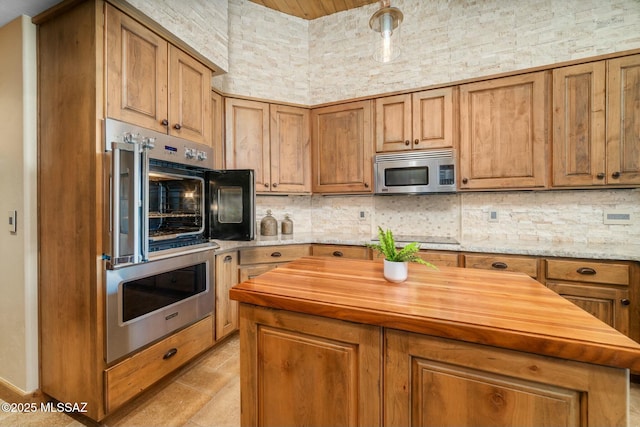 kitchen featuring tasteful backsplash, butcher block counters, a kitchen island, brown cabinets, and stainless steel appliances