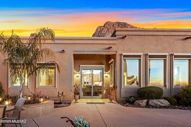 exterior entry at dusk featuring a patio and stucco siding